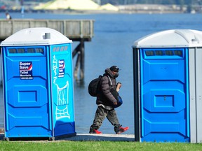 A man walks past portable toilets at Crab Park in Vancouver.