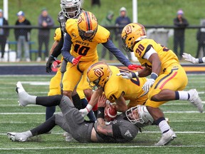 Gaels defenders Aidan Simpson, left, Eric Colonna and Joshua McBain surround Gee-Gees quarterback Ben Maracle during Saturday's game in Kingston.