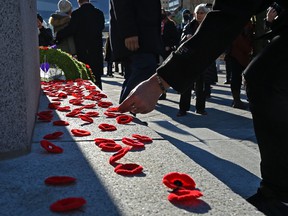 Attendees of the Remembrance Day ceremony place red poppies in the cenotaph outside Edmonton City Hall on November 11, 2021.