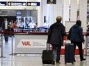Travelers walk through Trudeau International Airport in Montreal on Monday, Nov. 29, 2021.
