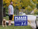 Rob Guthrie and his pet Nash observe the fast-paced traffic outside their home on Avondale Avenue on Thanksgiving.  The Guthries recently erected a new sign in the city of Windsor urging motorists to slow down.