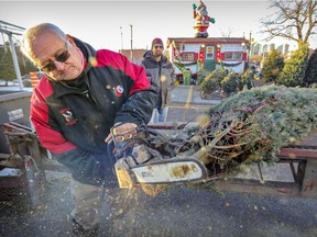 Marcel Viens trims the bottom of a Christmas tree for customer Brad Phillips at Atwater Market on December 1, 2021.