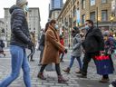Masked pedestrians cross Union St. on Sainte-Catherine St. in Montreal on Friday, Dec.11, 2020. 