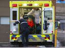Paramedics load a patient into an ambulance outside a Montreal hospital emergency department on Tuesday, December 21, 2021.