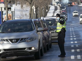 A Montreal police officer directs drivers to the COVID testing and vaccination center at the Olympic Stadium on December 21, 2021.
