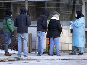 A healthcare worker instructs people lining up for a COVID-19 test at the Hôtel Dieu testing site in Montreal on Friday, December 24, 2021.