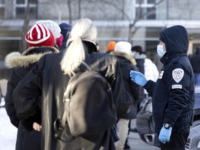 A security guard helps manage the line for COVID-19 testing at the Hôtel Dieu testing site in Montreal on Friday, December 24, 2021.