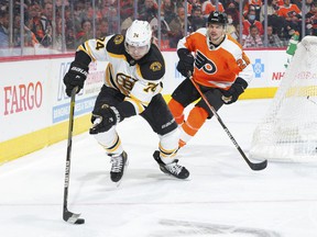Boston Bruins winger Jake DeBrusk controls the puck against Scott Laughton and the Philadelphia Flyers during an NHL game Nov. 20 in Philadelphia.