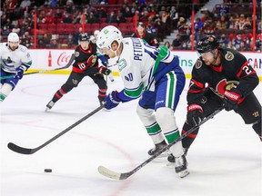 Elias Pettersson # 40 of the Vancouver Canucks protects the puck of Dylan Gambrell # 27 of the Ottawa Senators during the first period at the Canadian Tire Center on December 1, 2021 in Ottawa, Ontario.
