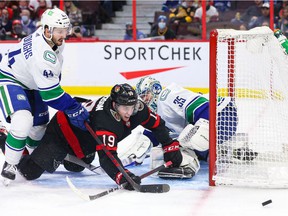 Kyle Burroughs # ​​44 of the Vancouver Canucks fights for the loose puck with Drake Batherson # 19 of the Ottawa Senators during the second period at the Canadian Tire Center on December 1, 2021 in Ottawa, Ontario.