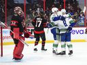Ottawa Senators goalkeeper Filip Gustavsson looks up as Vancouver Canucks Bo Horvat, left to right, Conor Garland and Tanner Pearson celebrate a goal during first period of NHL action in Ottawa on Wednesday, December 1. of 2021.