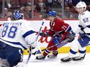 Montreal Canadiens center Jake Evans (71) tries to shoot Tampa Bay Lightning goalkeeper Andrei Vasilevskiy (88) as Lightning defender Cal Foote (52) puts pressure on him during NHL first period action. in Montreal, Tuesday, December 7, 2021..