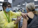 Retired nurse Jennifer Martin vaccinates Lisette Bashour at a COVID-19 vaccination site in Décarie Square in Montreal on Monday, March 1, 2021.