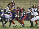 Montreal Alouettes running back William Stanback burrows a hole when offensive lineman Sean Jamieson blocks Hamilton Tiger-Cats Lee Autry II, left, during the game in Montreal on August 27, 2021. The Ticats' Eddy Wilson II searches the tackle. 