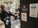 An employee washes walls in front of posters indicating the total number of customers allowed in a store in the Complexe Desjardins on Friday, December 4, 2020.