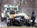 Montreal police and towing crews remove a car that lost control and overturned the guardrail of Sources Blvd. flyover landing on Donegani Street in Montreal, Saturday, December 18, 2021. 