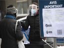 Individuals receive a ticket for a later appointment to obtain a rapid COVID-19 test kit at a pharmacy at the corner of St-Laurent Blvd. and Mont-Royal Ave. on Monday, December 20, 2021.