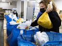 MONTREAL, QUE.: December 22, 2021 - Volunteer Nancy Saltarelli packs food baskets at the Sun Youth Organization on Wednesday.  Saltarelli has two children who also volunteered to assemble the baskets.