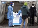 Health workers and security personnel greet people at a combined vaccination and testing clinic on Center St. in Montreal on December 22, 2021. 