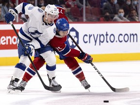 Montreal Canadiens center Jake Evans (71) and Tampa Bay Lightning left wing Ross Colton (79) battle to regain the puck during the third period in Montreal, Tuesday, Dec. 7, 2021.
