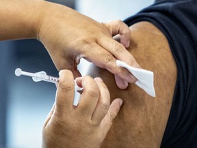 A vaccinator administers a dose of the COVID-19 vaccine in Montreal.