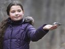 A bird eats from the hand of 10-year-old Allie Brown at Ojibway Park in Windsor on Tuesday, Dec. 21, 2021.