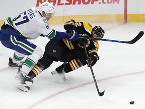 Canucks defender Tyler Myers puts the wood on Boston Bruin Tomas Nosek during last Sunday's game in Boston.  The Bruins visit Rogers Arena on Wednesday.