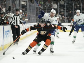 Anaheim Ducks 'Isac Lundestrom, up front, skates on Vancouver Canucks' Tanner Pearson as he swings the puck during the first period of an NHL hockey game on Wednesday, December 29, 2021, in Anaheim, California.