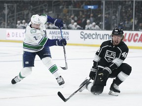 Vancouver Canucks 'Luke Schenn, left, shoots under the defense of Los Angeles Kings' Brendan Lemieux during the first period of an NHL hockey game Thursday, Dec. 30, 2021, in Los Angeles.