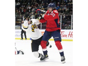 Windsor Spitfires forward Kyle McDonald, right, knocks down Sarnia Sting's Theo Hill in the first period of Friday's game.