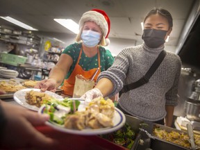 Volunteers Michele Fera, left, and Eileen Dancel serve a Christmas dinner at the Mission Center on Christmas Day, Saturday, December 25, 2021.