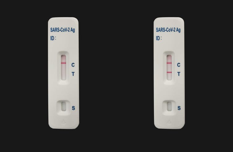 Two COVID-19 test devices, one negative and one positive, on a black background