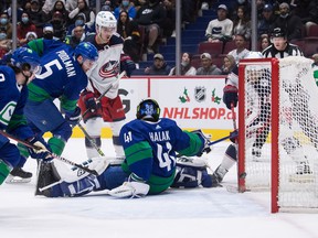 Columbus Blue Jackets 'Max Domi, back right, scores against Vancouver Canucks goalkeeper Jaroslav Halak (41) while Columbus's Tucker Poolman (5) and Columbus' Jack Roslovic (96) watch during the first period of a hockey game the NHL in Vancouver on Tuesday.  December 14, 2021.