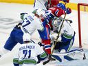 Artturi Lehkonen of the Montreal Canadiens is pushed over Vancouver Canucks goalkeeper Thatcher Demko by defender Tyler Myers (57) during second period of NHL hockey action in Montreal, Monday, Nov. 29, 2021.