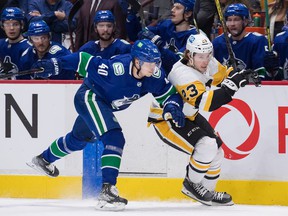 Canucks center Elias Pettersson attempts to stop a speedy Brock McGinn of the Pittsburgh Penguins during their NHL game Dec. 4, 2021 at Rogers Arena.