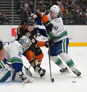 Vancouver Canucks goalkeeper Thatcher Demko, defender Quinn Hughes (43) and Anaheim Ducks center Sam Carrick (39) battle against the net in the first period of the game at the Honda Center.