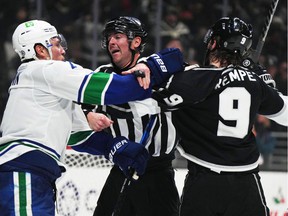 NFL referee Tom Chmielewski (center) tries to break up a fight between Vancouver Canucks defender Luke Schenn (2) and LA Kings center Adrian Kempe (9) in the second period at Crypto.com Arena.