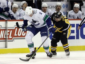 Vancouver Canucks defender Tucker Poolman and Pittsburgh Penguins captain Sidney Crosby battle for control of the puck on November 24, 2021.