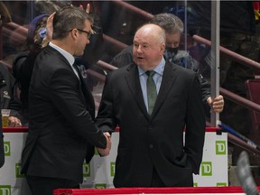 New Vancouver Canucks assistant coach Scott Walker congratulates new head coach Bruce Boudreau on his first win over the Los Angeles Kings in the third period at Rogers Arena.  Vancouver won 4-0.