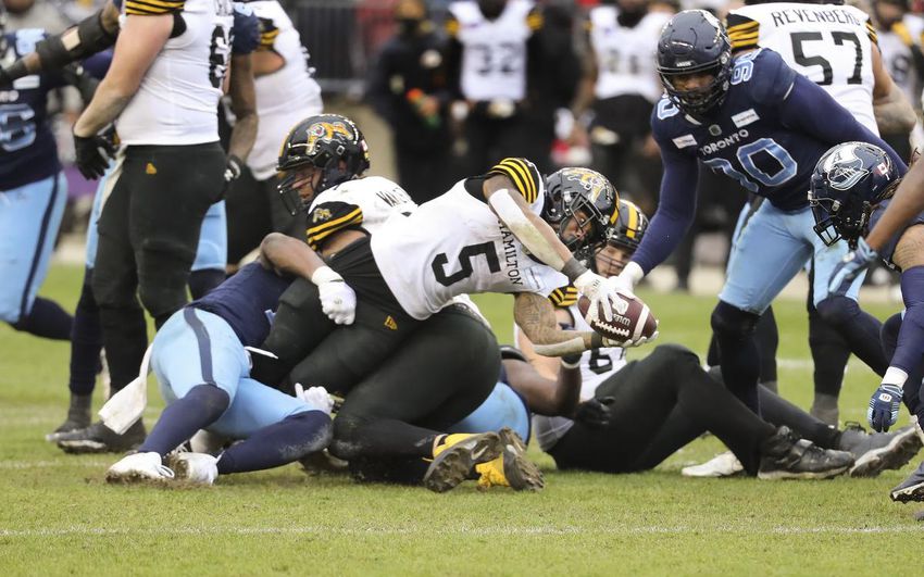 Tiger-Cats running back Don Jackson reaches an extra yard in Hamilton's East final victory over Toronto.  The Ticats will play at home in next week's Gray Cup.