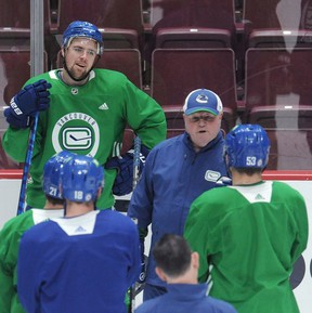Veteran winger Tanner Pearson (top left) and other Canucks, including captain Bo Horvat (right), pay attention as new head coach Bruce Boudreau delivers his message during practice at Rogers Arena on Tuesday.