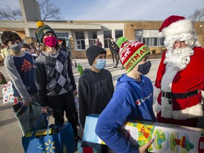Xavier Seguin, 11, a sixth-grade student at St. Andre Catholic Elementary School, joins his classmates as they fill a school bus with toys and food they have collected for those in need, Friday, December 10, 2021 Items collected will go to the Children's Aid Society and the Sandwich Teen Action Group.