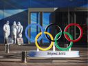 Workers in PPE on December 30 stand next to the Olympic rings within the closed-circuit area near the National Stadium, or the Bird's Nest, where the opening and closing ceremonies of the Olympic Winter Games will take place. Beijing 2022, in Beijing, China.