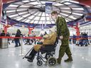A member of the Canadian Armed Forces takes a woman to a COVID-19 vaccination clinic at the Olympic Stadium in Montreal, Thursday, January 6, 2022.