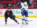 OTTAWA, ONTARIO - DECEMBER 1: Artem Zub # 2 of the Ottawa Senators does a stickcheck to JT Miller # 9 of the Vancouver Canucks as he attempted to play the puck during the first period at the Canadian Tire Center on December 1, 2021 in Ottawa , Ontario.