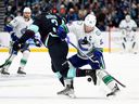 SEATTLE, WASHINGTON - JANUARY 1: Will Borgen #3 of the Seattle Kraken and Bo Horvat #53 of the Vancouver Canucks battle for a loose puck during the first period at Climate Pledge Arena on January 1, 2022 in Seattle, Washington.
