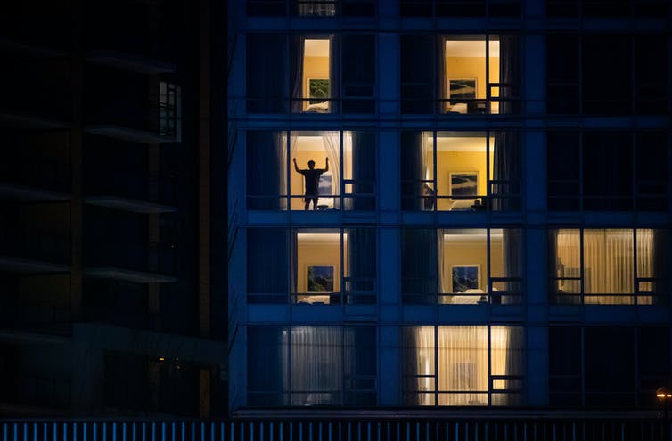 A person is seen in silhouette closing the curtains on a hotel room window.