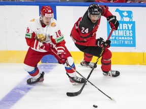 Canada's Justin Sourdif (24) and Russia's Pavel Tyutnev (18) battle for the puck during the third exhibition period of the IIHF World Junior Hockey Championship in Edmonton, Thursday, December 23, 2021.