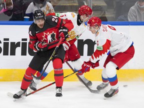 Canadian Justin Sourdif (24) fights for the puck with Russians Kirill Steklov (6) and Fedor Svechkov (9) during the second exhibition period of the IIHF World Junior Hockey Championship in Edmonton, Thursday, December 23, 2021.