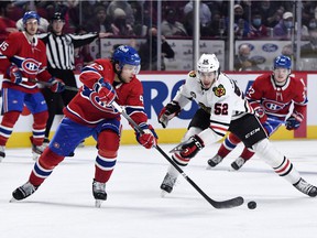 Montreal Canadiens defenseman Kale Clague plays the puck as Chicago Blackhawks forward Reese Johnson checks the front end during the game at the Bell Center on December 9, 2021.